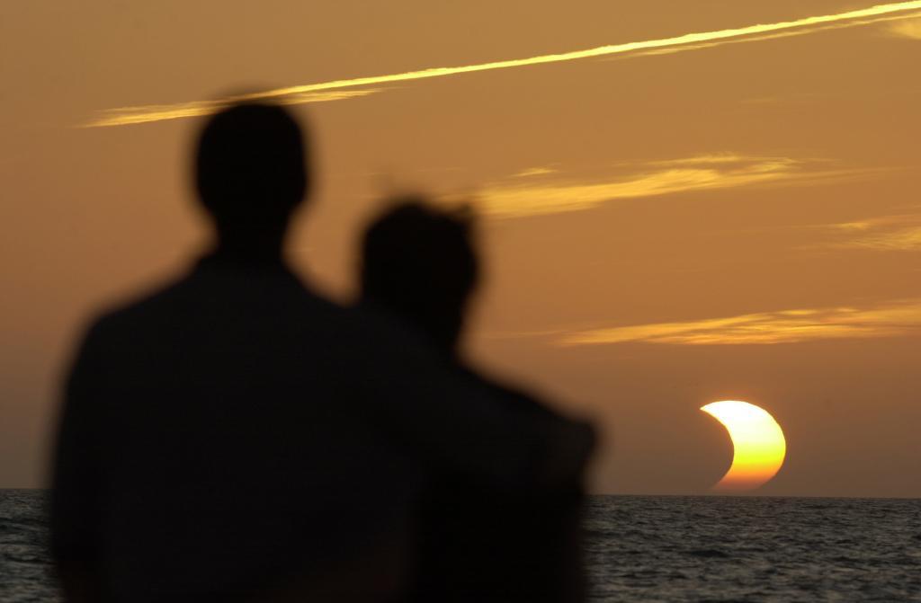 Two people watch the solar eclipse, which was partially visible along the Florida coast