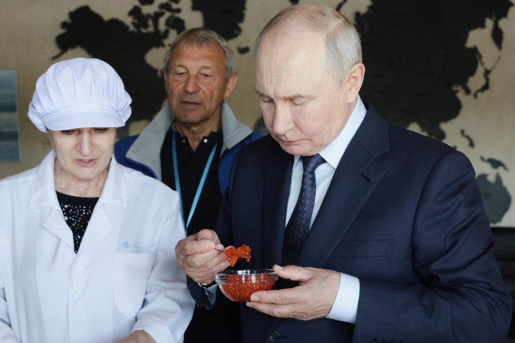 Russian President Vladimir Putin, right, tastes products as he visits the Yasny fish processing complex at Kitovoye village on the Iturup Island,
