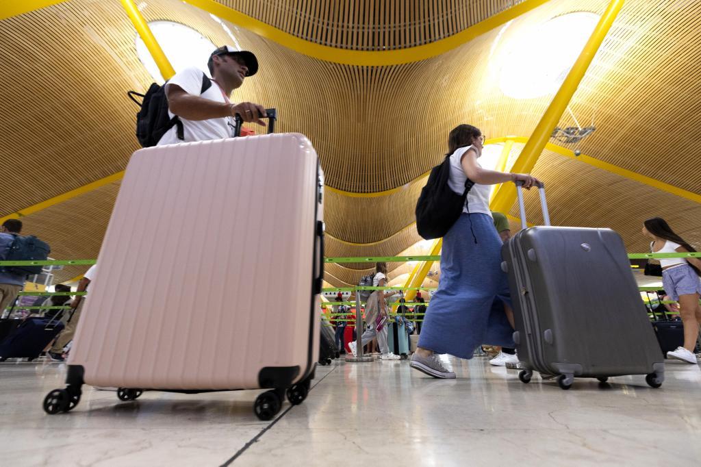 Passengers carry their luggage at the Madrid airport.