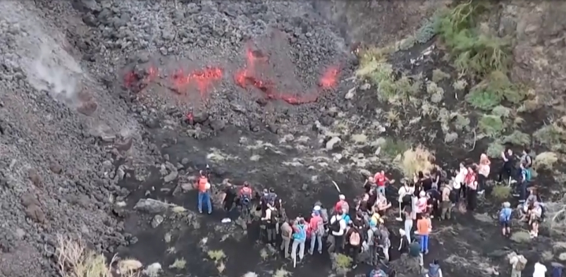 Tourists just a few meters from lava flows following the eruption of Mount Etna