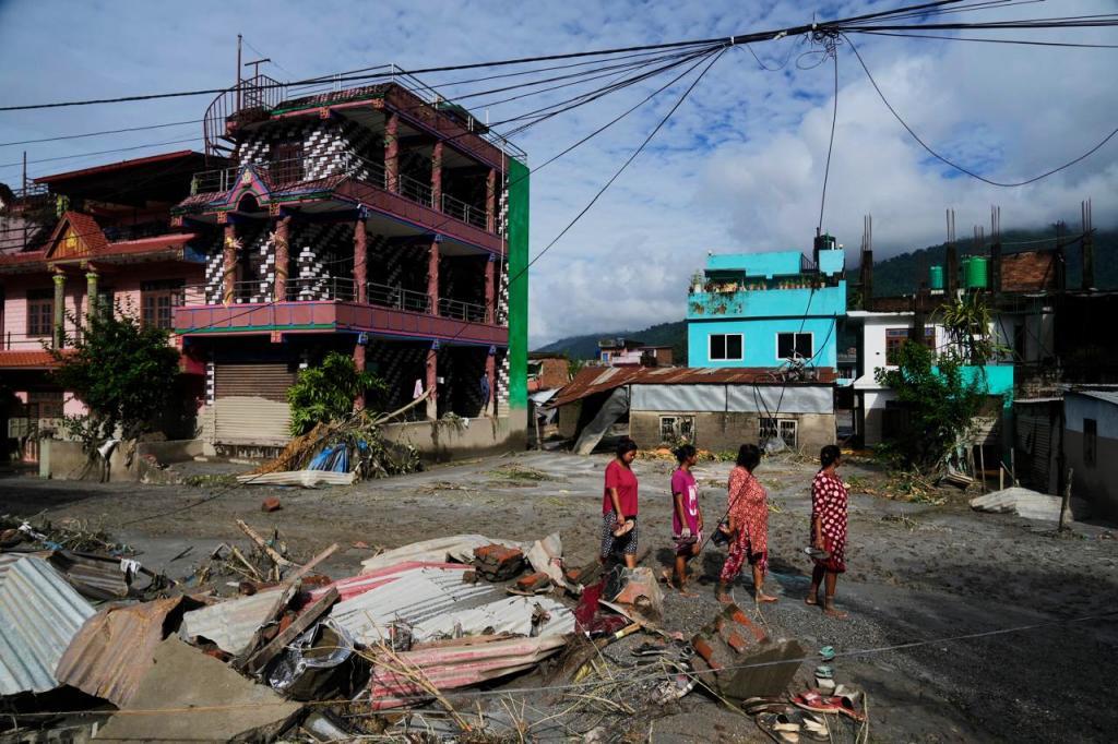 People walk past damage in the aftermath of flash floods in Devighat in the Nuwakot district in Nepal