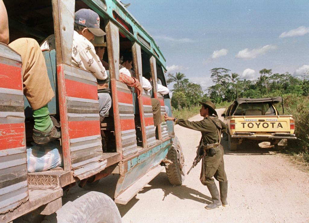 Image of a rebel, a guerrilla fighter with the Revolutionary Armed Forces of Colombia (FARC), stopping a bus at a checkpoint in La Machaca