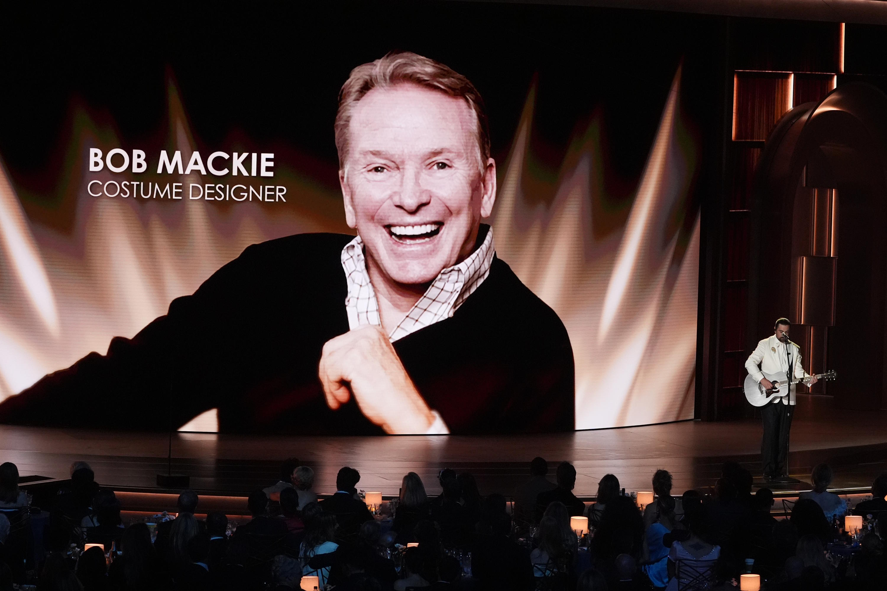 An image of Bob Mackie is shown while Noah Kahan performs "Bridge Over Troubled Water" during an in memoriam presentation.
