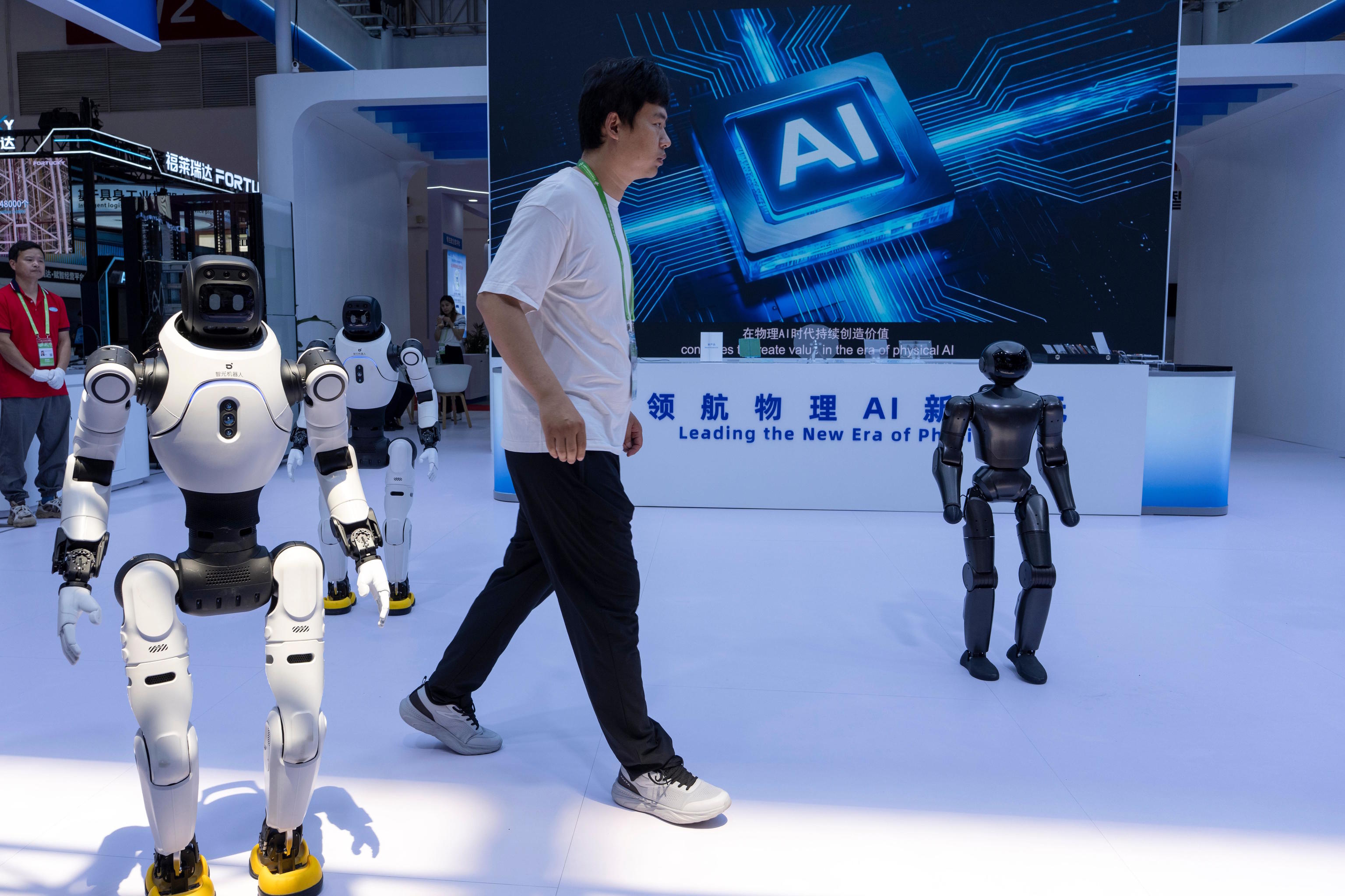 A worker passes by robots from Chinese company Lens at the China International Supply Chain Expo in Beijing.