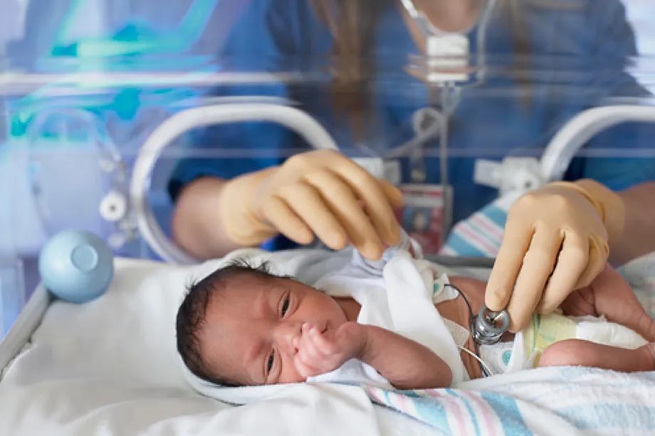 A professional examines a baby in an incubator.