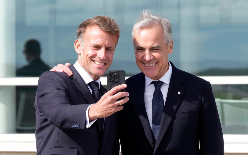 French President Emmanuel Macron, left, takes a selfie with Canadian Prime Minister Mark Carney