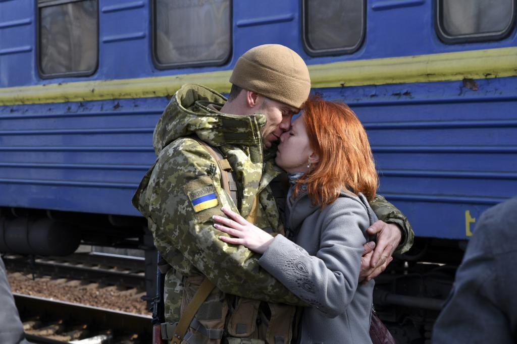 A couple embrace prior to the woman boarding a train carriage leaving for western Ukraine, at the railway station in Kramatorsk,