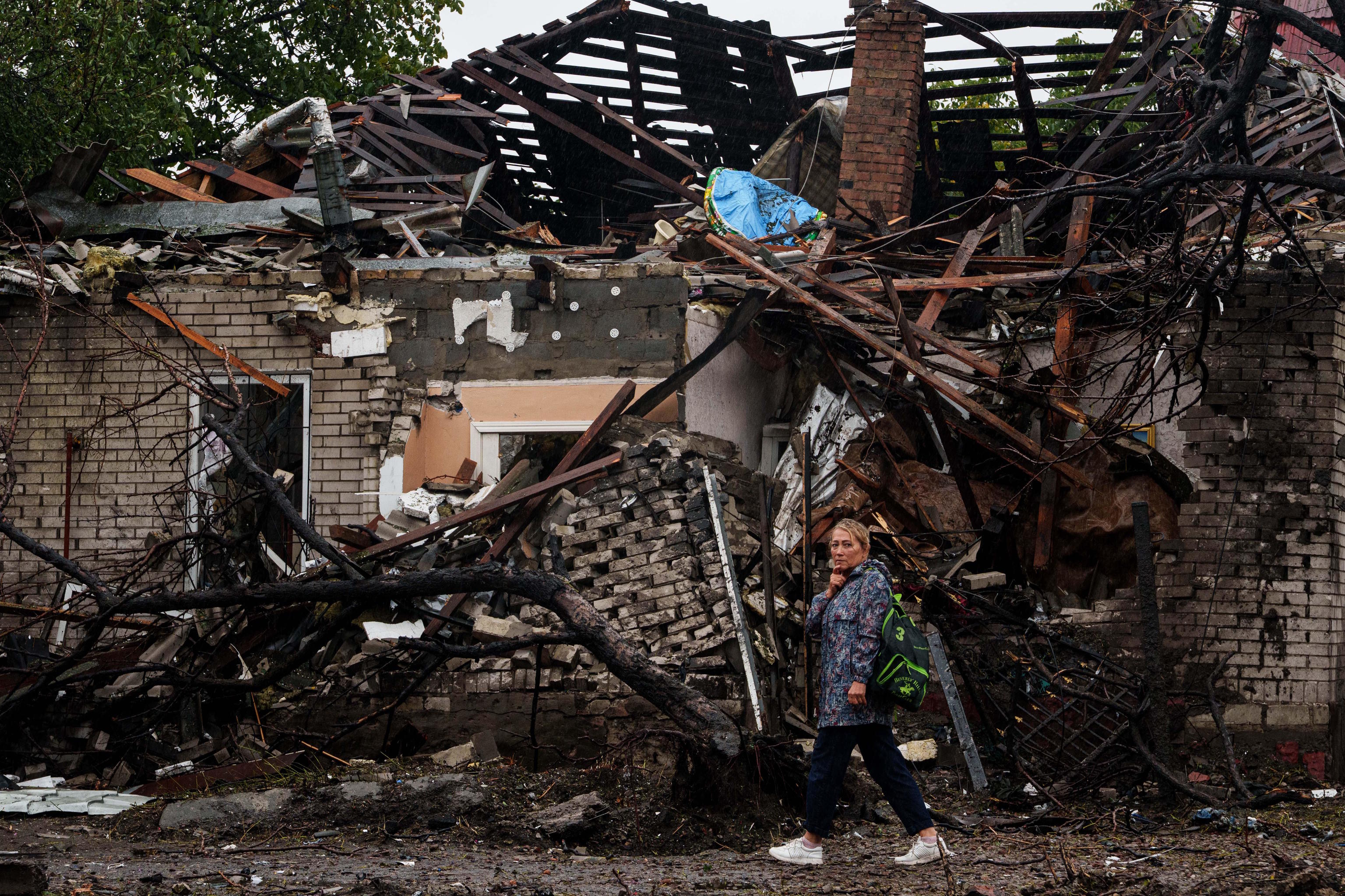A woman walks in front of a house destroyed in a Russian strike on a residential neighbourhood in Kyiv.