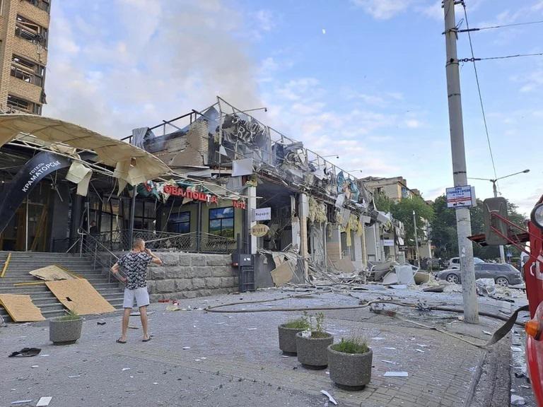 A man stands on a street in front of a shop and restaurant RIA Pizza destroyed by a Russian attack in Kramatorsk