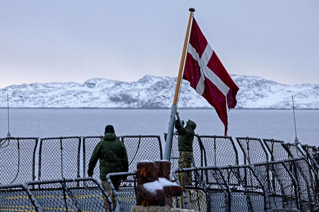 Danish soldiers raise the Danish flag on the navy ship HDMS V�dderen