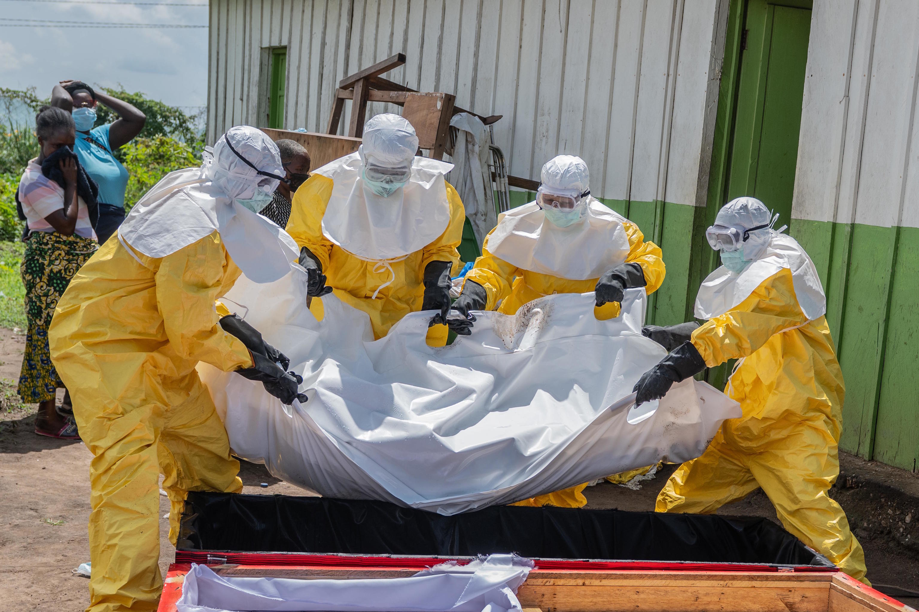 Red Cross workers place the body of a person who died of Ebola into a coffin in Rwampara, Congo.