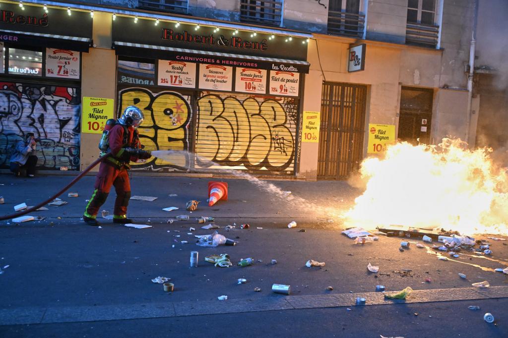 A firefighter extinguishes a fire during clashes with the police