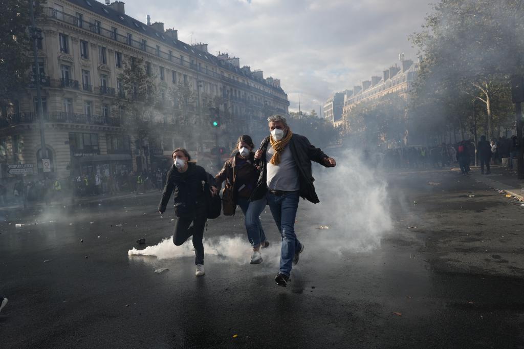 Protesters run to leave the Republique square during a demonstration against rising living costs,