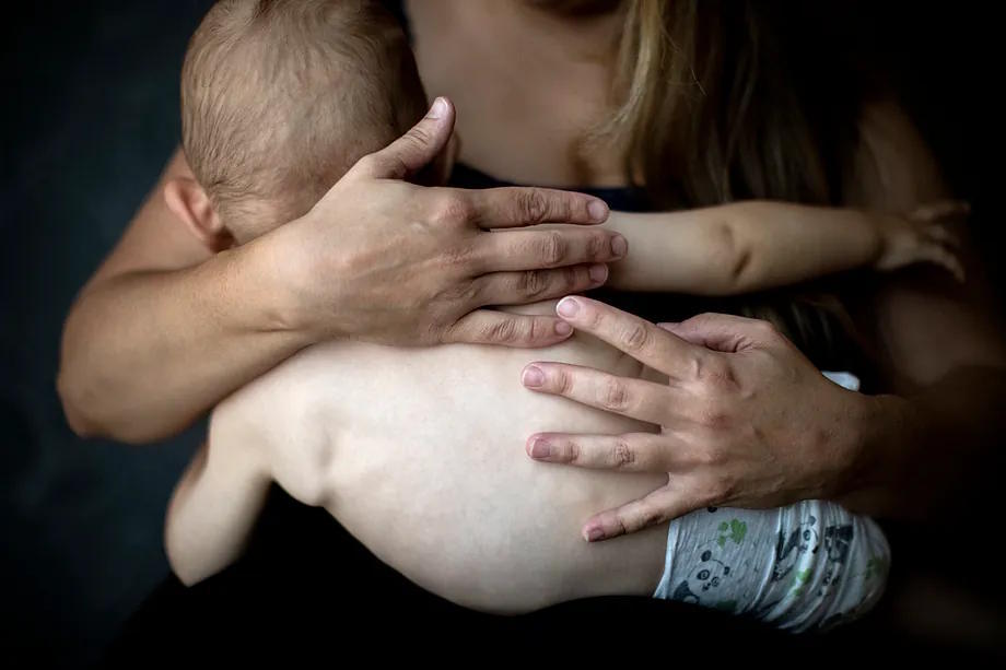 A woman cuddles her baby close to her chest.