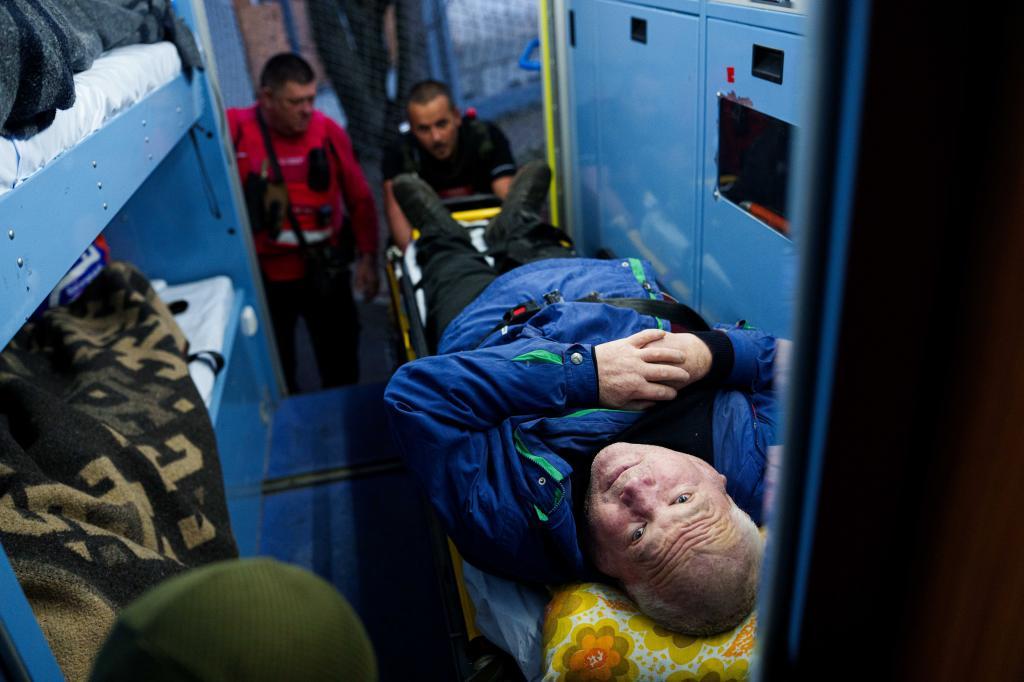 Red Cross volunteers move a man with a disability on a stretcher into an ambulance